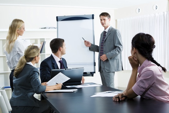 Image of smart business people looking at their leader while he explaining something on whiteboard during seminar